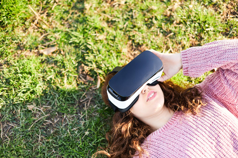 Eine Frau mit VR Brille liegt im Gras. Technologie für NGOs