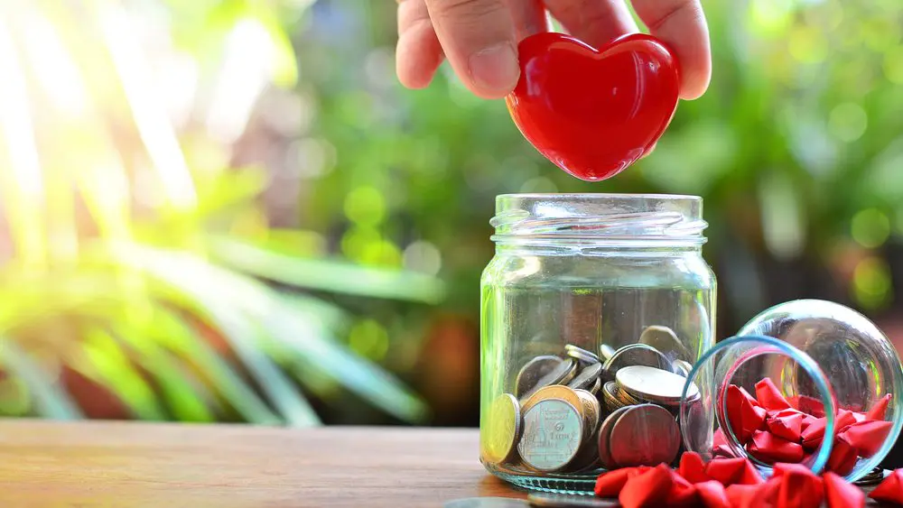 Münzen und rote Herzen in einem Glas stellen Philanthropie symbolisch dar