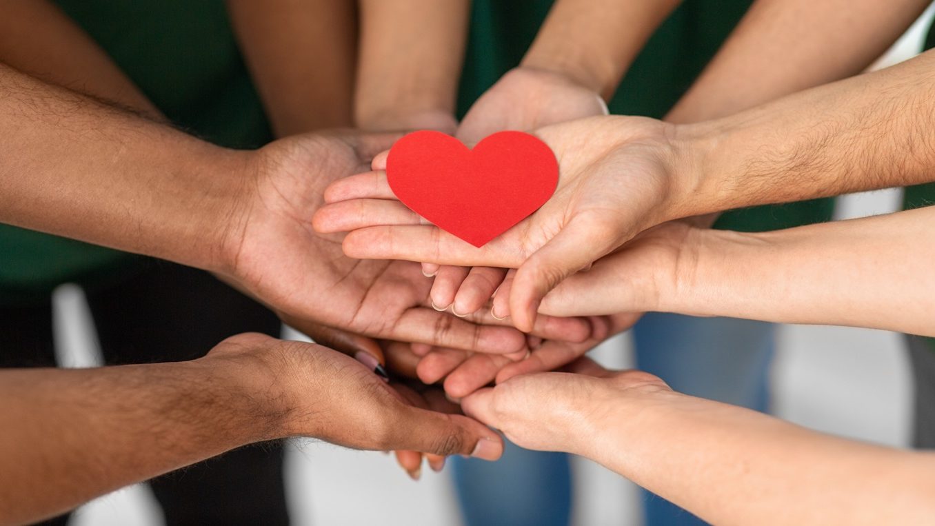Mehrere Menschen halten gemeinsam ein Herz aus Papier.
