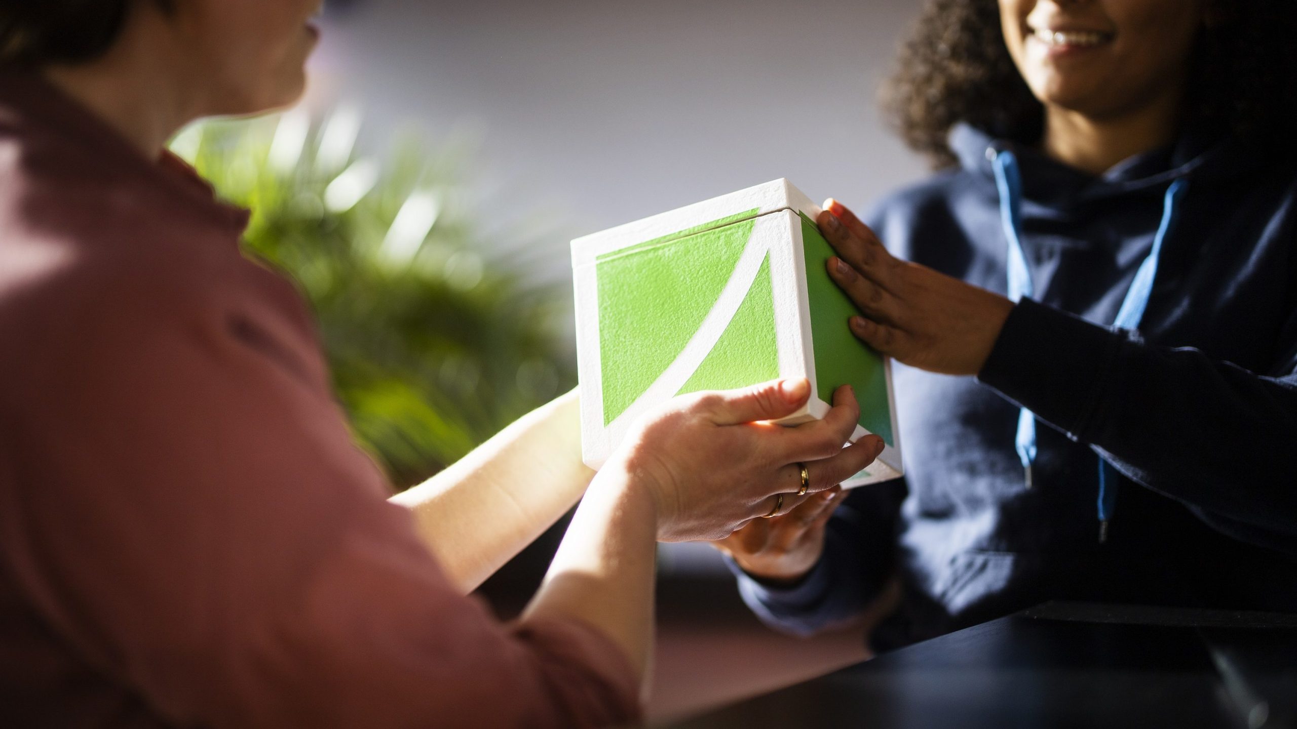 Zwei Personen halten einen FundraisingBox-Würfel aus Holz in der Hand