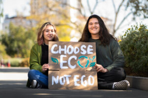 Zwei junge Menschen halten ein Schild, auf dem Choose Eco not Ego steht